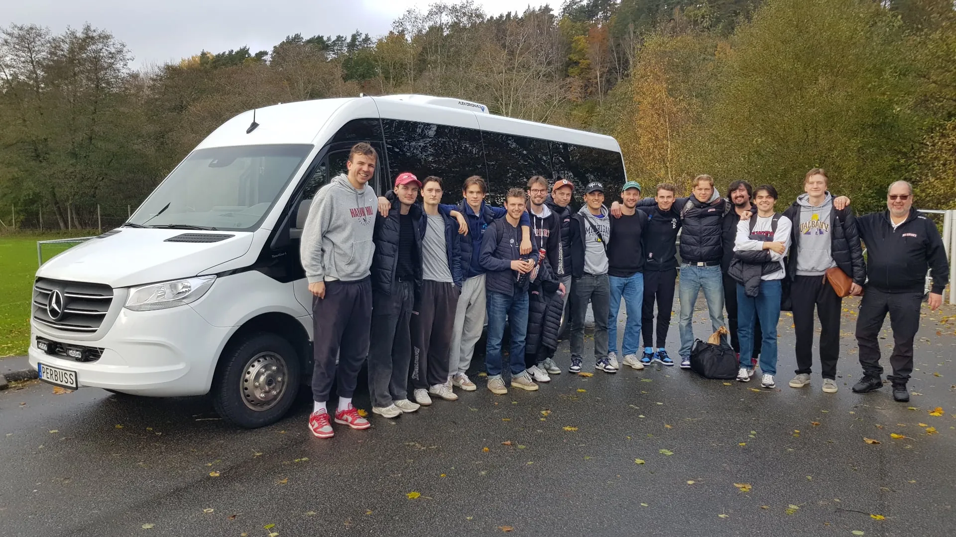 PerBuss – vit Mercedes-buss parkerad utanför en tegelbyggnad